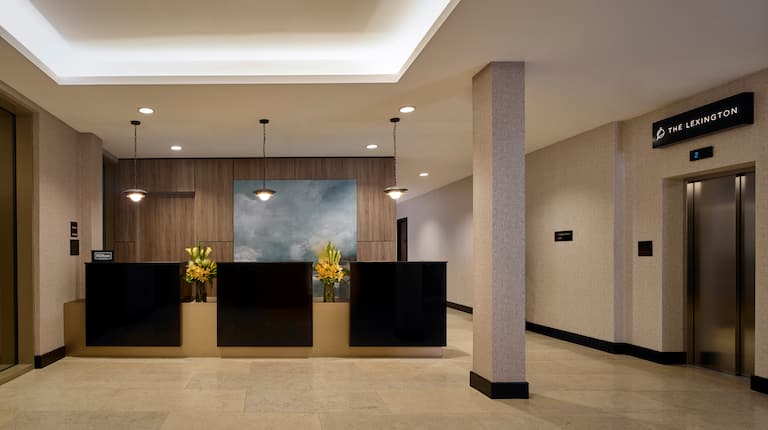 Hotel Front Desk Reception Area with Modern Brown and Tan Decor and Fresh Flowers with Granite Floor and Grand Ceiling