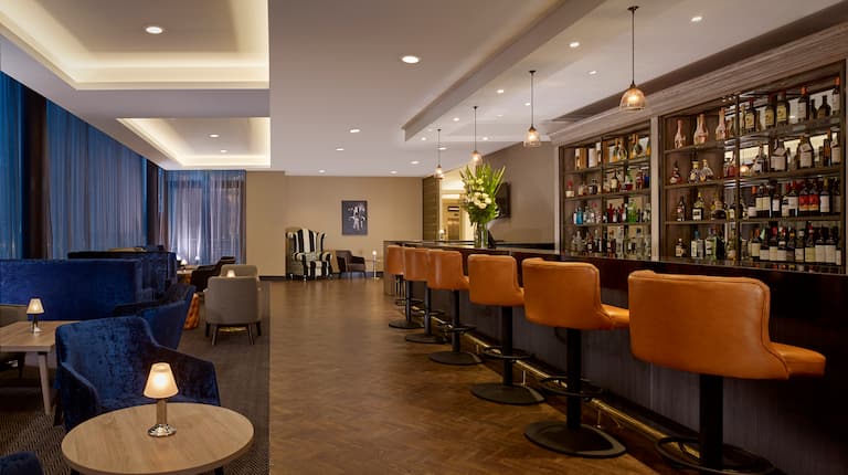 Hotel Lounge with Seating at the Bar and Booths along a Wall of Windows with View of the City