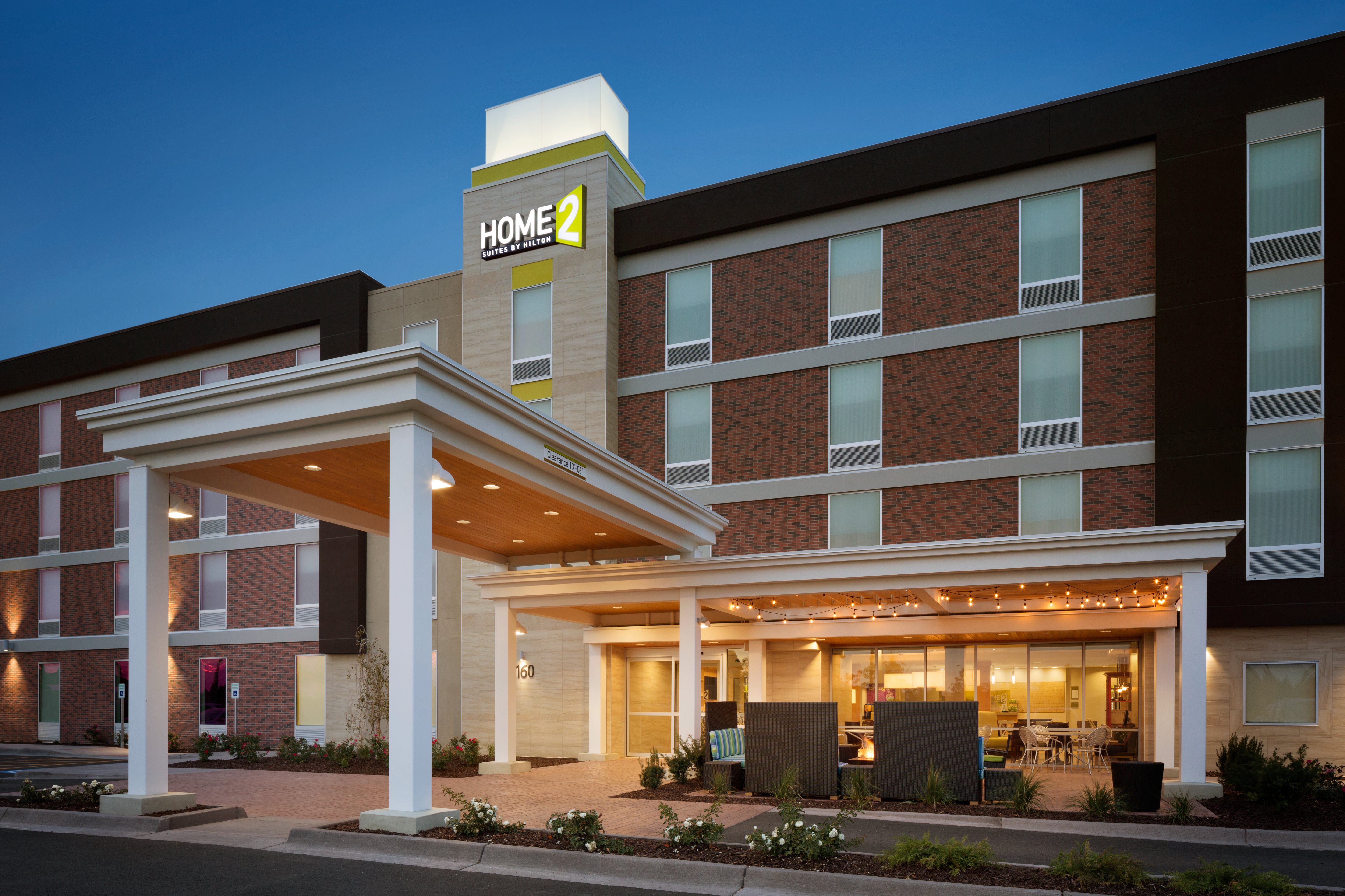 Angled View of Hotel Exterior, Signage, Entrance, and Landscaping Illuminated at Dusk