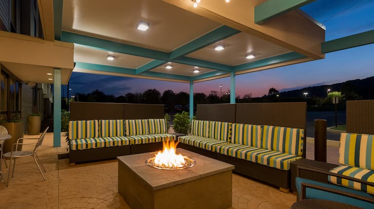Illuminated Outdoor Lounge With Soft Seating Around Fire Pit at Night