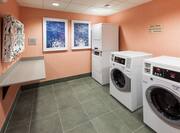 Laundry Room With Coin Operated Washers, Dryers, Folding Table, and Wall Art