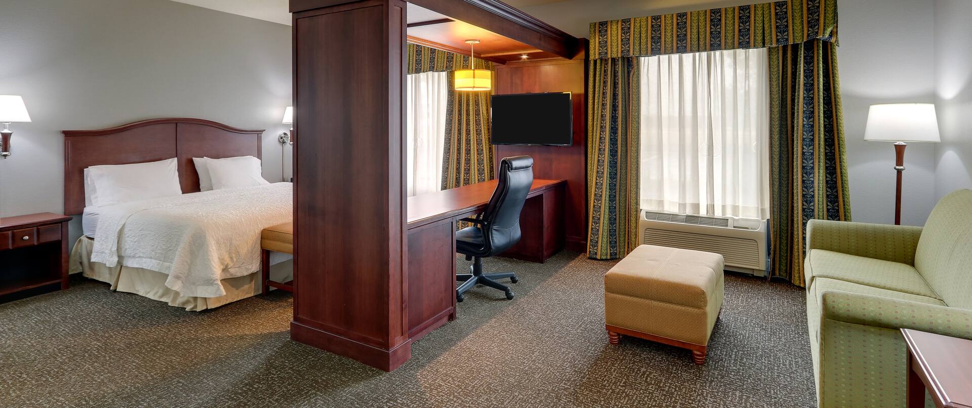 Suite with seating area, desk and double bed
