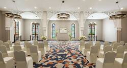 Spacious on-site meeting room featuring stunning stained glass windows and wedding ceremony setup with floral archway.