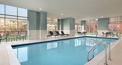 Spacious indoor swimming pool featuring accessible chair lift, ample seating, and floor to ceiling windows.