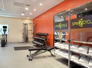A Fitness Center with Weights, Cardio Machines and Towels on a Shelf
