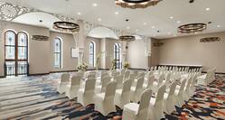 Spacious meeting room featuring wedding ceremony setup with ample seating, floral archway, and stunning stained glass windows.