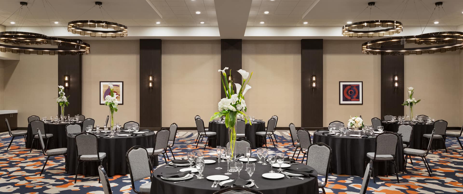 spacious meeting room banquet set up, round tables, chairs, dinner ware, flower centerpieces