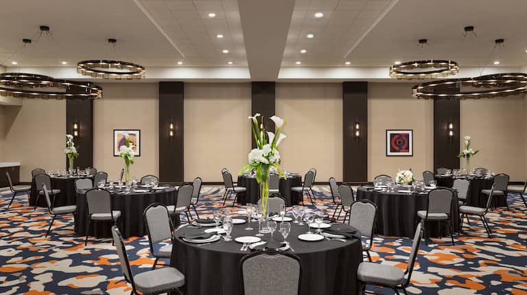 spacious meeting room banquet set up, round tables, chairs, dinner ware, flower centerpieces