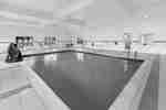 Alternate indoor pool view featuring blue water, pool steps, and surrounding deck.