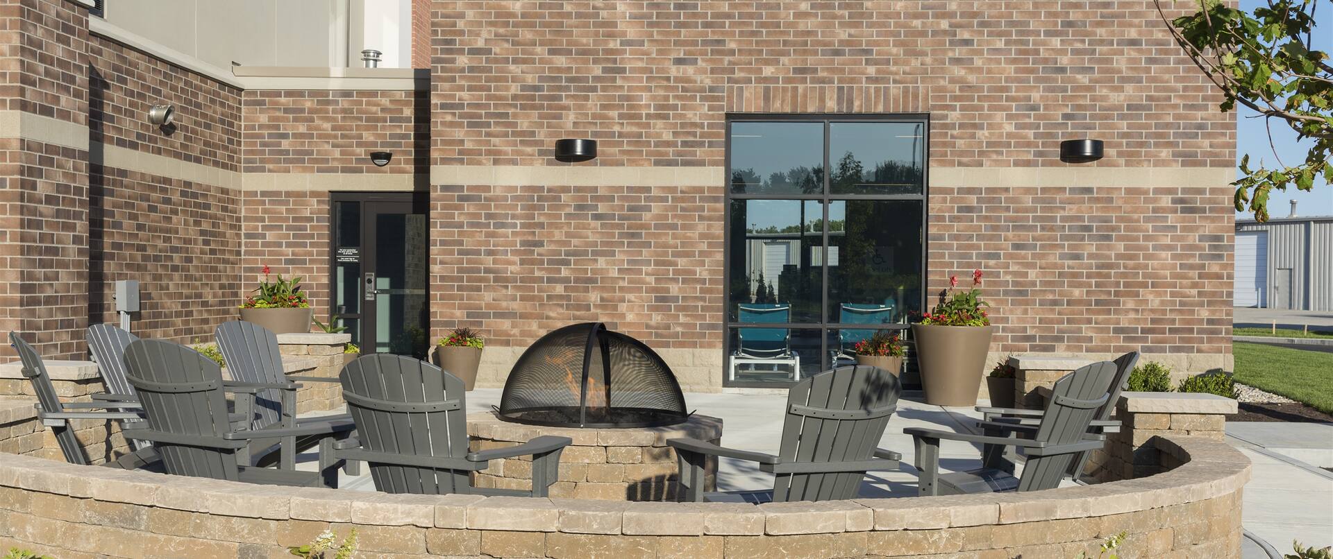 Chairs Around Fire Pit on Outdoor Patio by Hotel Exterior and Landscaping