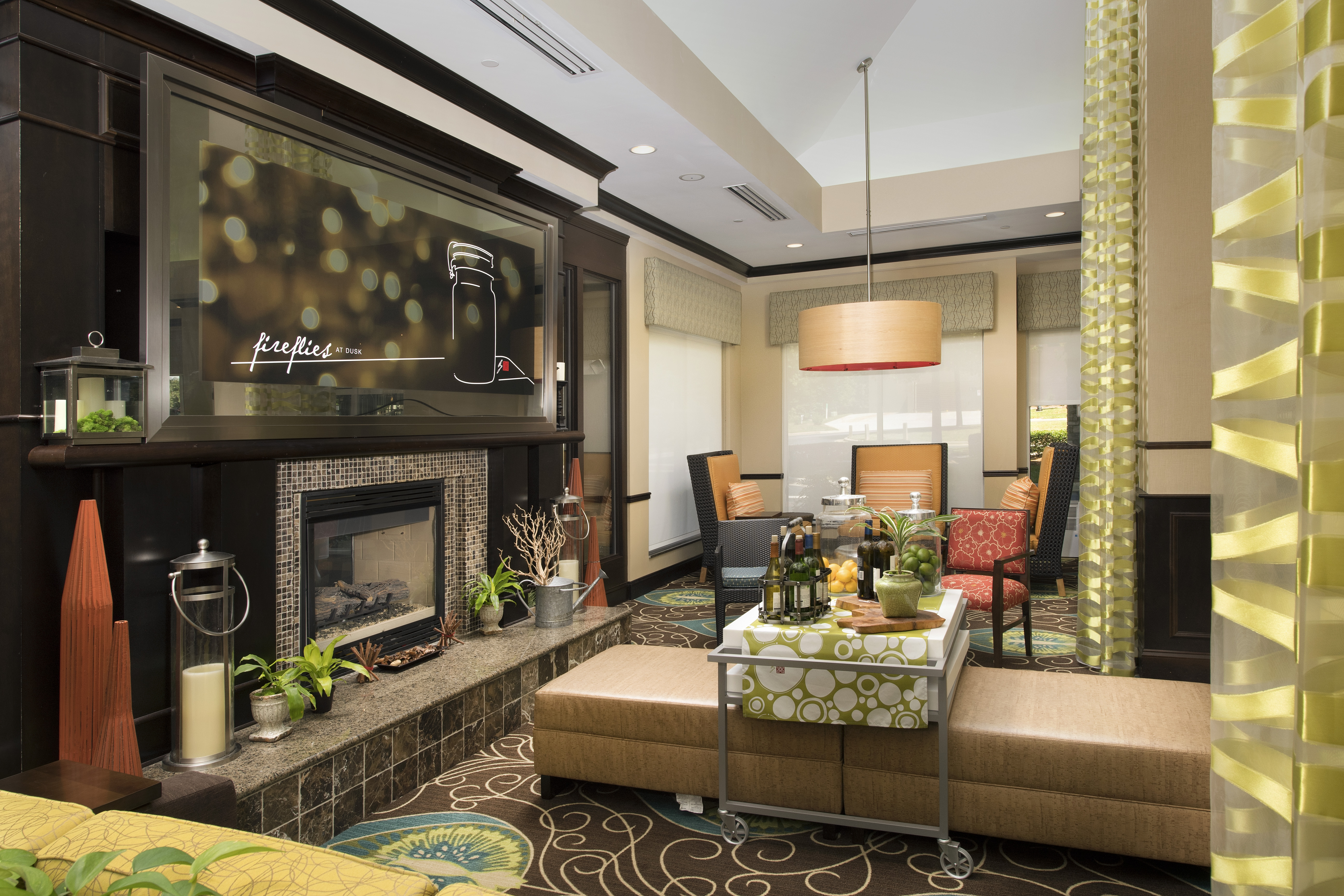 Lobby Seating Area With Long Drapes, Wall Art Above Fireplace, and Beverage Station