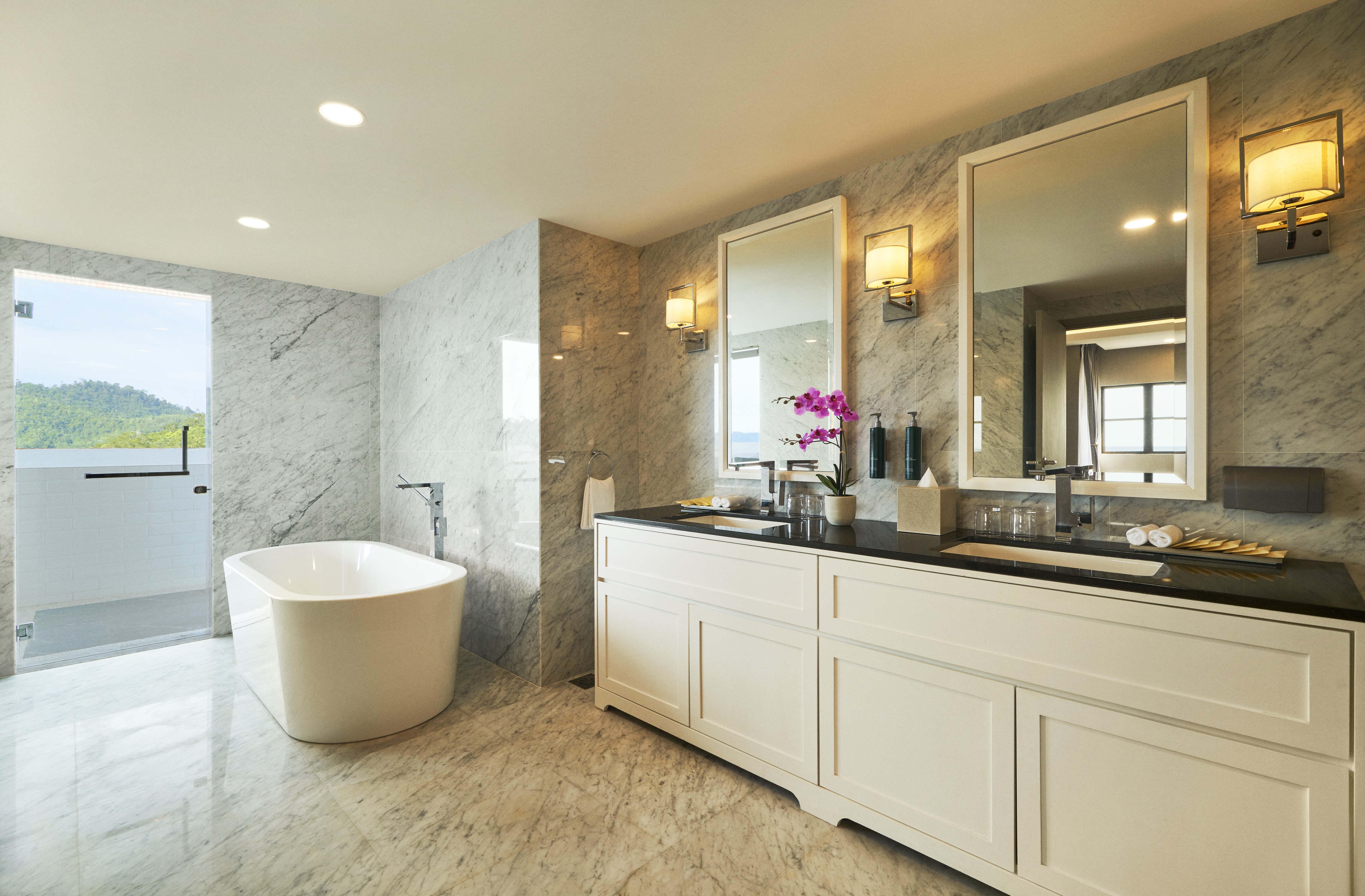 Dual Vanity Area with Amenities and a Bathtub in a Suite