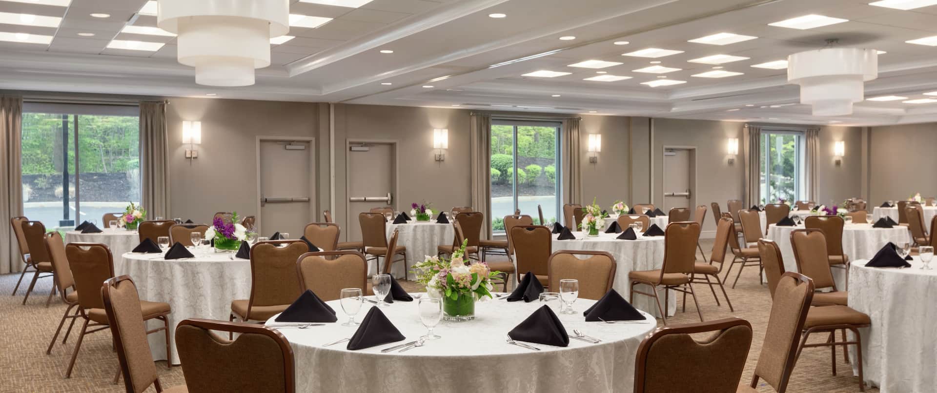Spacious combined meeting rooms fully equipped with banquet setup, beautiful floral center pieces, and large windows.