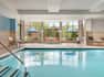 Beautiful indoor pool featuring hot tub, ample seating, and bright windows.