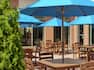 Beautiful outdoor patio for on-site bar featuring lush greenery, patio chairs, and tables with umbrellas.