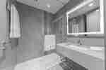 Ducha y área de tocador con espejo iluminado en la habitación
