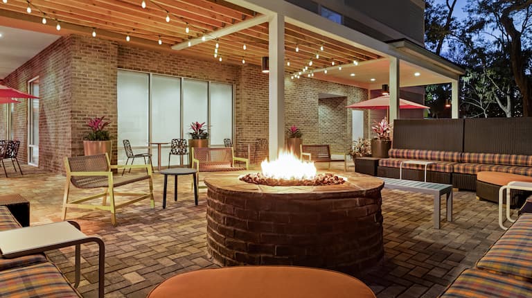 Beautiful outdoor lounge area featuring comfortable sofa style seating, string lights, and firepit.