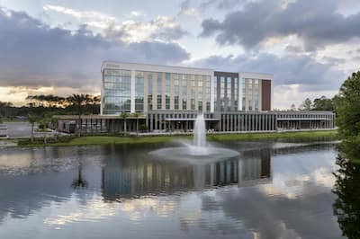 Hotel exterior with water in foreground and clouds overhead