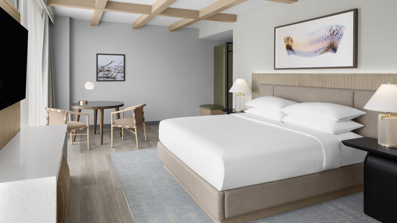 Bed in room with art on wall, TV and table