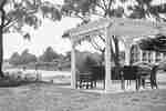 a pergola with chairs facing the water