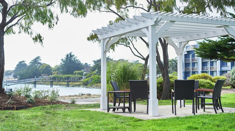 a pergola with chairs facing the water