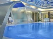 Indoor pool with water fountain and chaise lounges