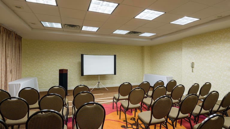  Meeting Room Arranged Theater Style With Rows of Chairs Facing Projector Screen