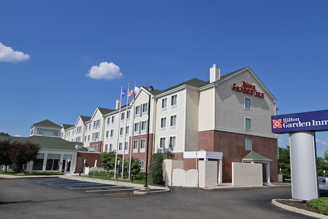 Angled View of Hotel Exterior, Signage, Flagpoles, Landscaping, and Parking Lot