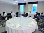 Place Settings and Napkins on Round Tables With WHite Linens in Meeting Room Set Up for Banquet