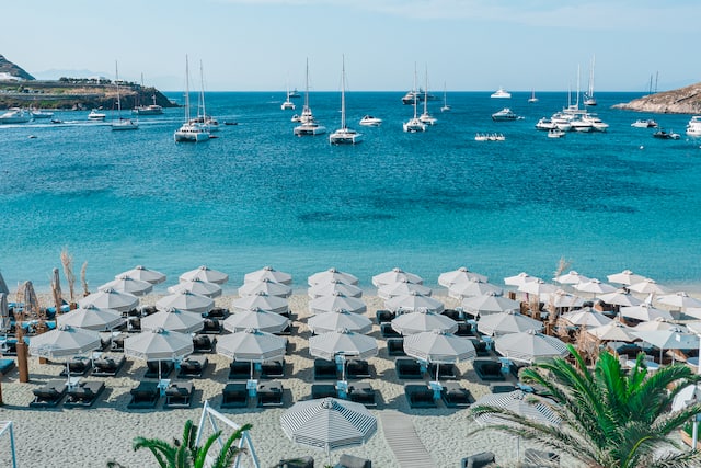 Strand mit Liegestühlen, Sonnenschirmen und Blick auf die Boote auf dem Wasser