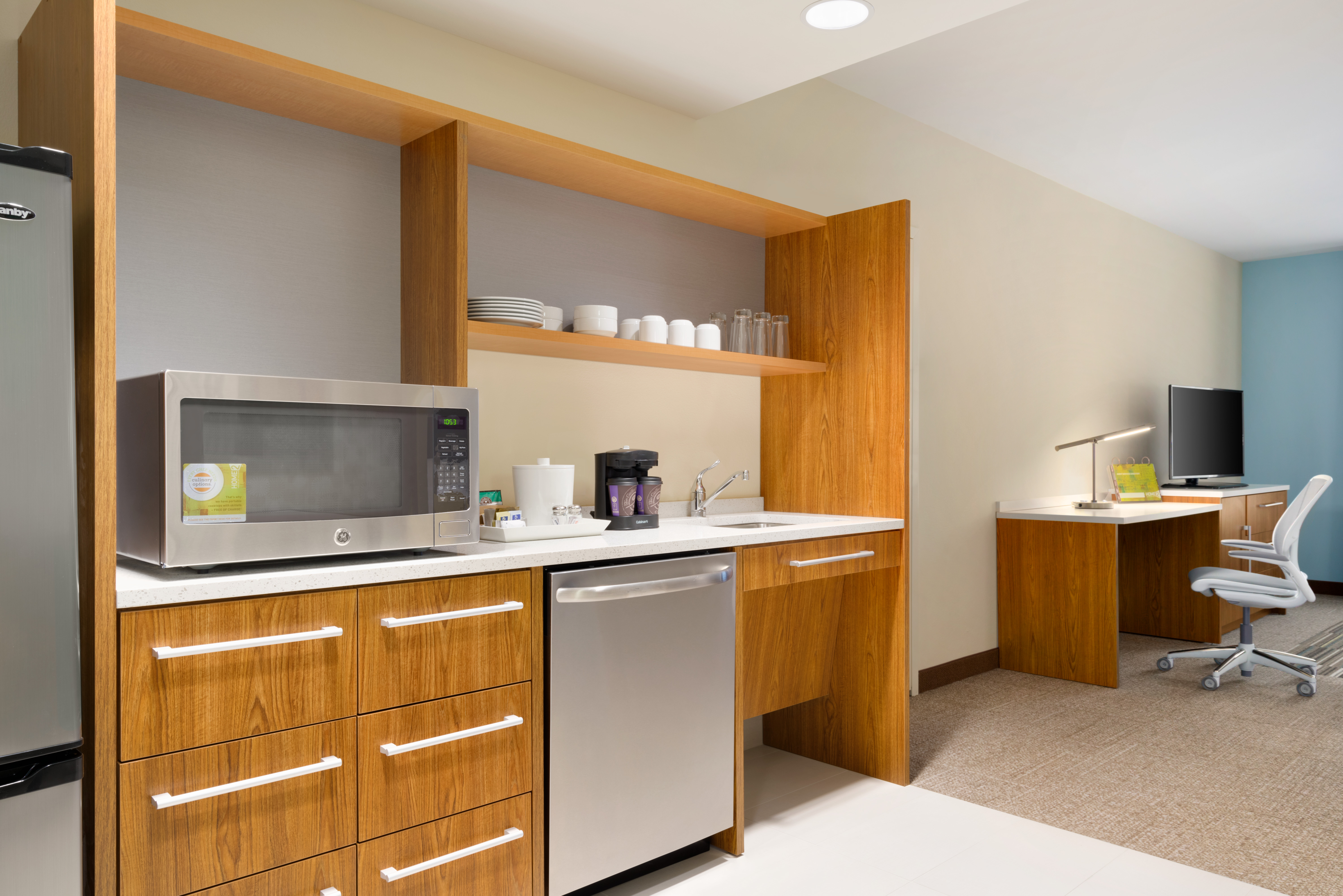 Guest Suite Kitchen Area with Microwave and Dishwasher Lounge Area Work Desk and HDTV in Background