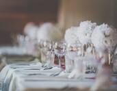 Wedding table setup with glasses and white floral centerpieces