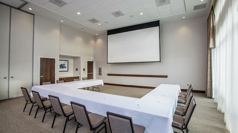 U-Shaped Table Setup in Meeting Room with Projector Screen
