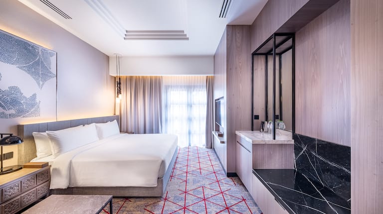 Guest room with a king bed and a wall-mounted TV.