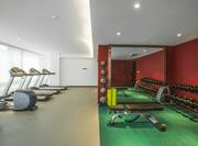 Fitness Center With Cardio Equipment Facing Large Window, Weight Balls, Large Mirror, Weight Bench, and Free Weights