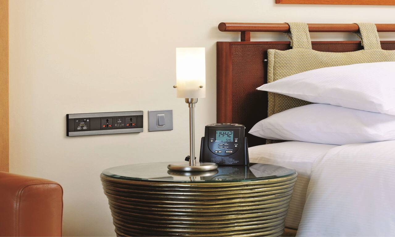 nightstand by bed with a variety of electrical outlets