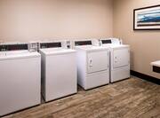 Laundry Room With Coin Operated Washer, Dryer, and Wall Art