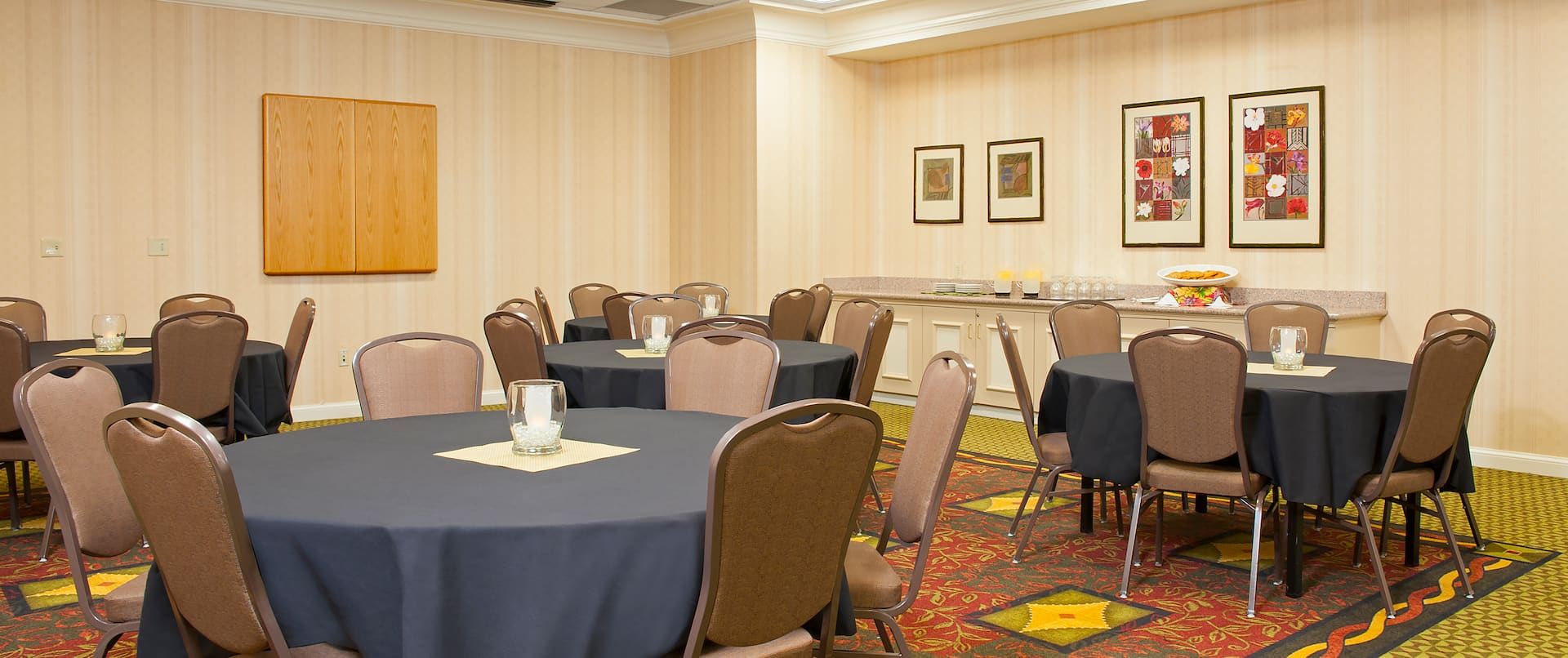 Banquet Set Up With Round Tables, Wall Art, and Refreshment Area in Meeting Space