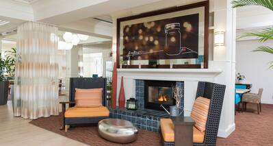 Large Art Featured Above Fireplace in Lobby Lounge Area With Two Chairs and Silver Table