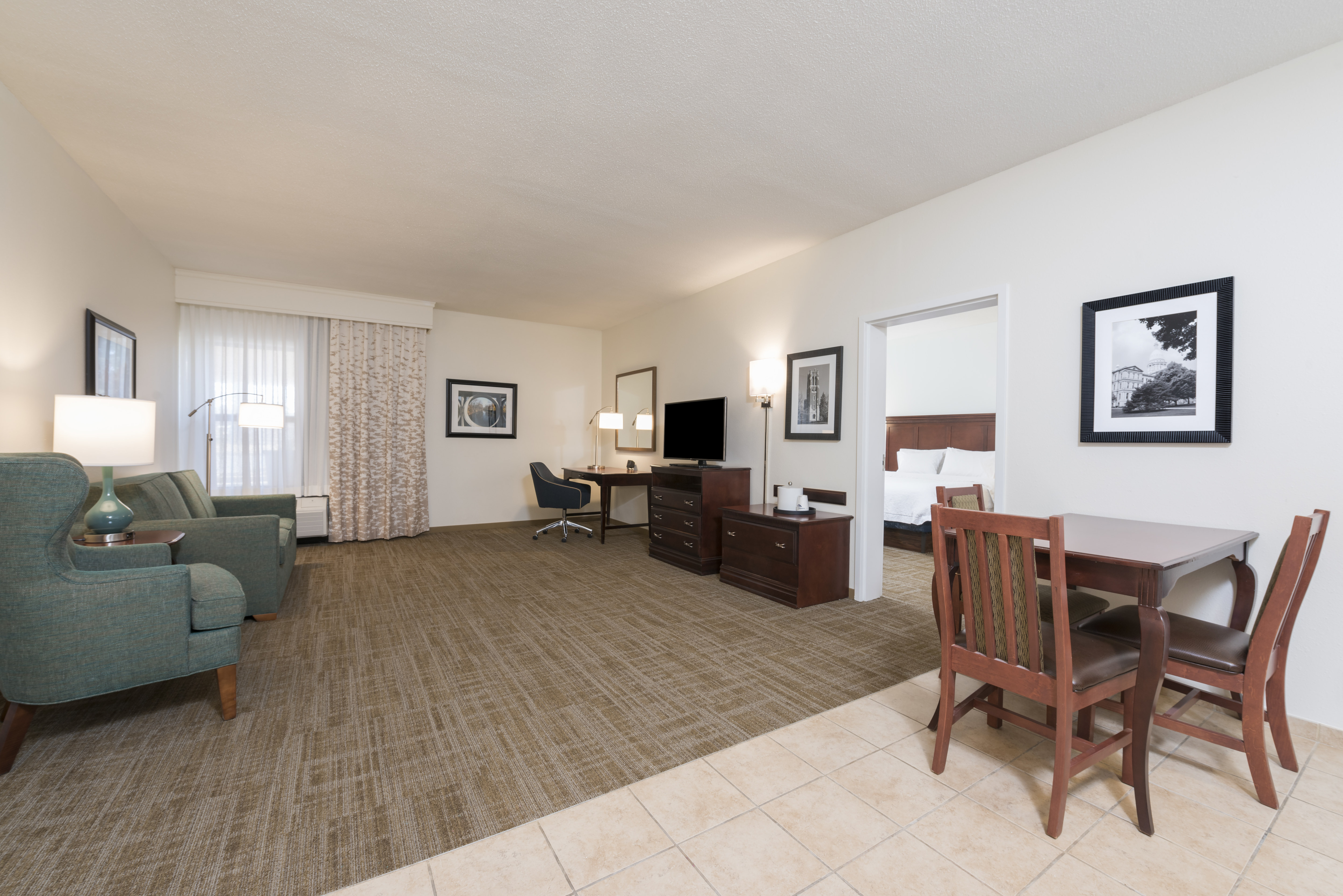 Suite Living Area with Lounge Seating, Table, Chairs, Work Desk, Television and Entry to Bedroom