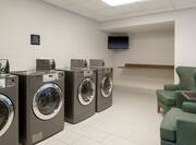 Guest Laundry Room with Coin-Operated Washing Machines and Two Armchairs