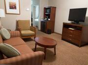 Sofa, Wall Art, Armchair, Tables, Microwave, Mini Fridge, and TV in Junior Suite Living Area