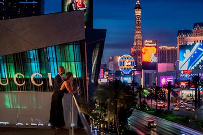 Personen auf der Dachterrasse mit Blick auf die Straßen mit Neonlicht