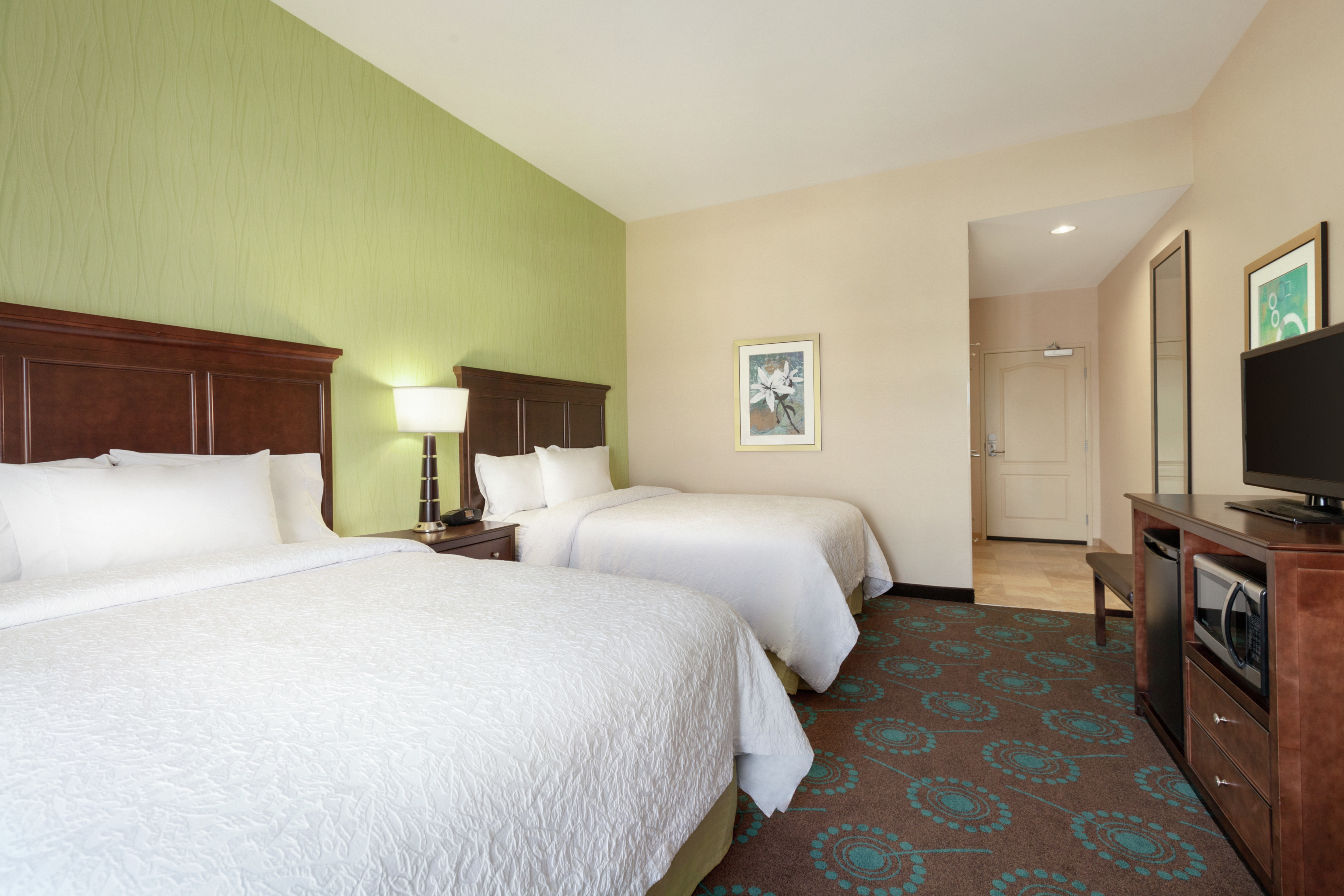 Spacious guestroom featuring two comfortable queen beds, TV, microwave, and mini fridge.