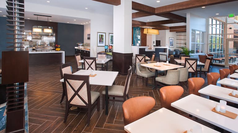 Tables and Chairs in Breakfast Dining Area With Views of Kitchen and front Desk in Background