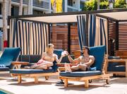 man and woman toasting drinks on outdoor lounge chairs