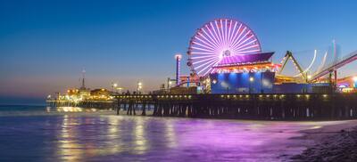 Night time view of Santa Monica pier with illuminatied ferris wheel and attractions
