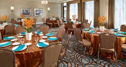 Round Tables With Gold Cloths, Turquoise Napkins, and White Vases With Flowers in Breakwater Banquet Room