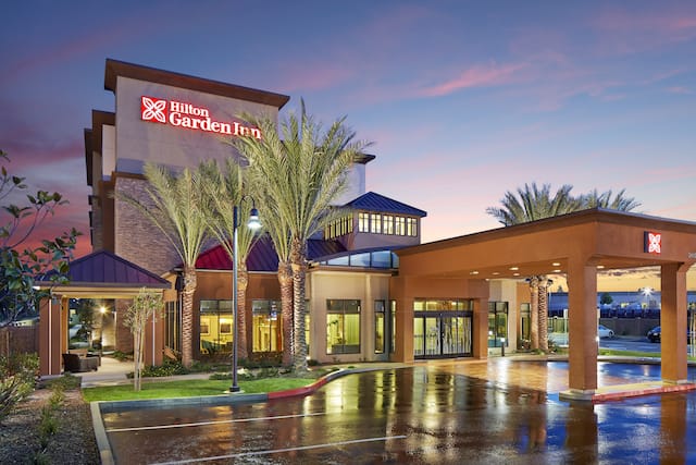 Hotel Exterior, Signage, Driveway, Landscaping, and Parking Lot Illuminated at Dusk