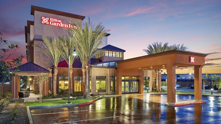 Hotel Exterior, Signage, Driveway, Landscaping, and Parking Lot Illuminated at Dusk
